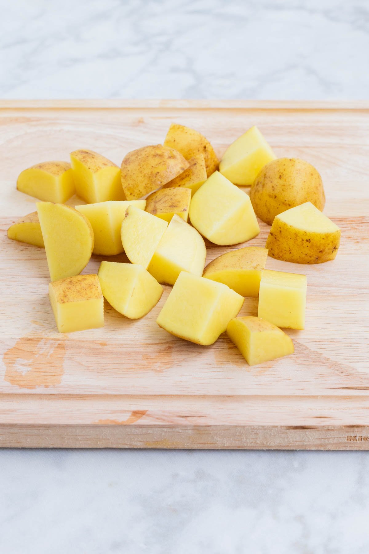 Potatoes are cubed on a cutting board.