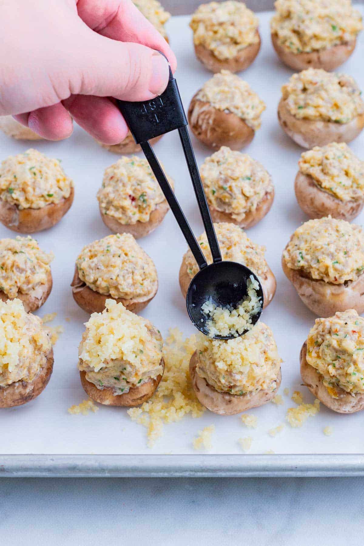 The cheesy breadcrumbs are sprinkled on top of the stuffed mushrooms.