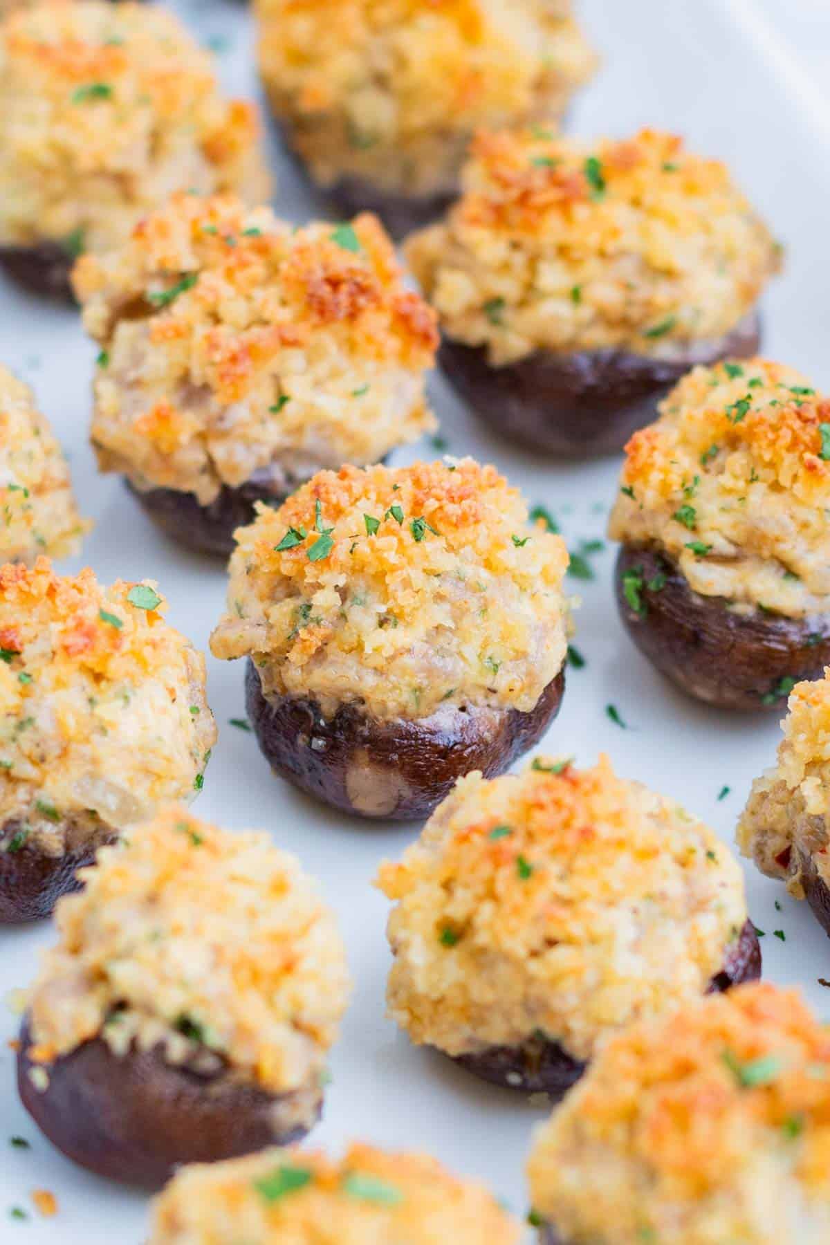 Mushrooms are stuffed with sausage and cheese then baked until golden, then served on a plate.
