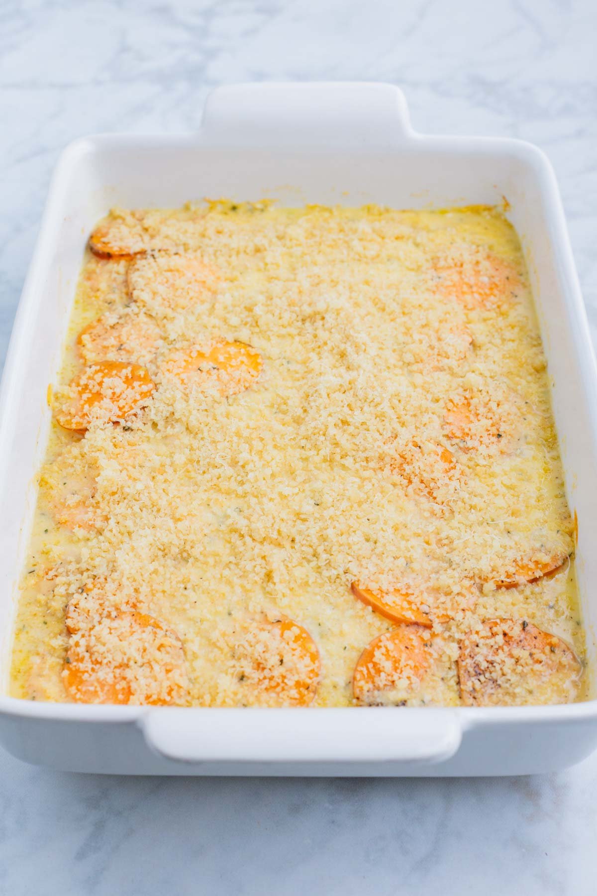 Sweet potato au gratin is prepared in a casserole dish.