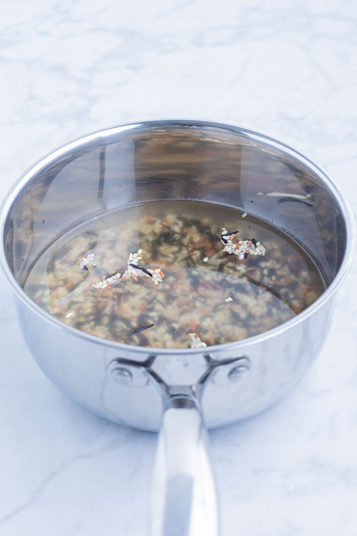 Wild rice is cooked in a pot on the stove.