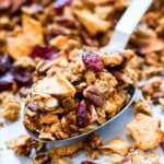 A metal spoon is scooping up homemade apple cinnamon granola.