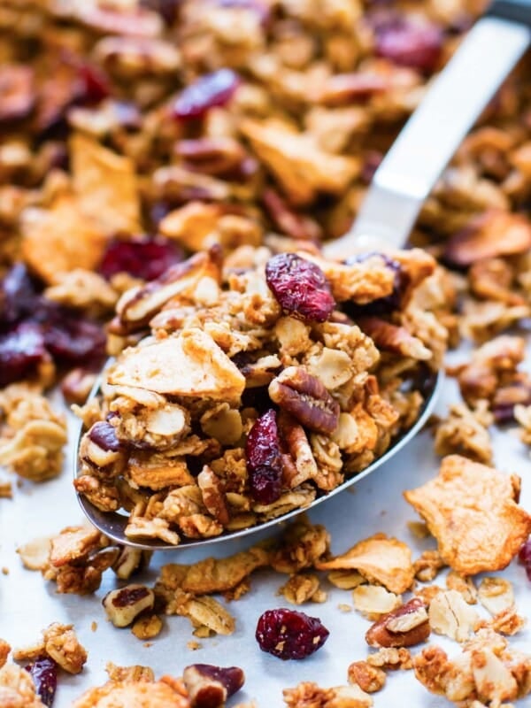 A metal spoon is scooping up homemade apple cinnamon granola.