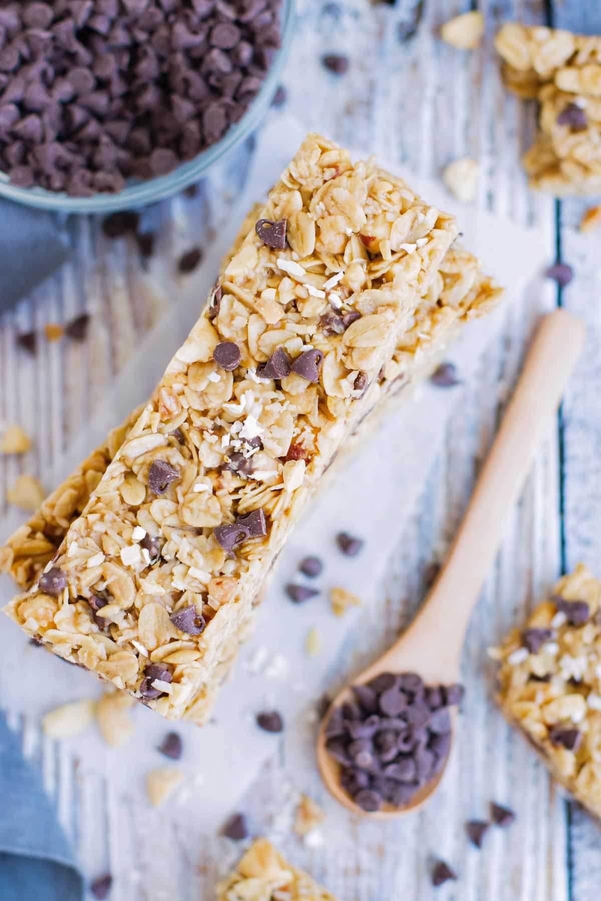 No bake granola bars in a pile with a bowl of chocolate chips on the side.