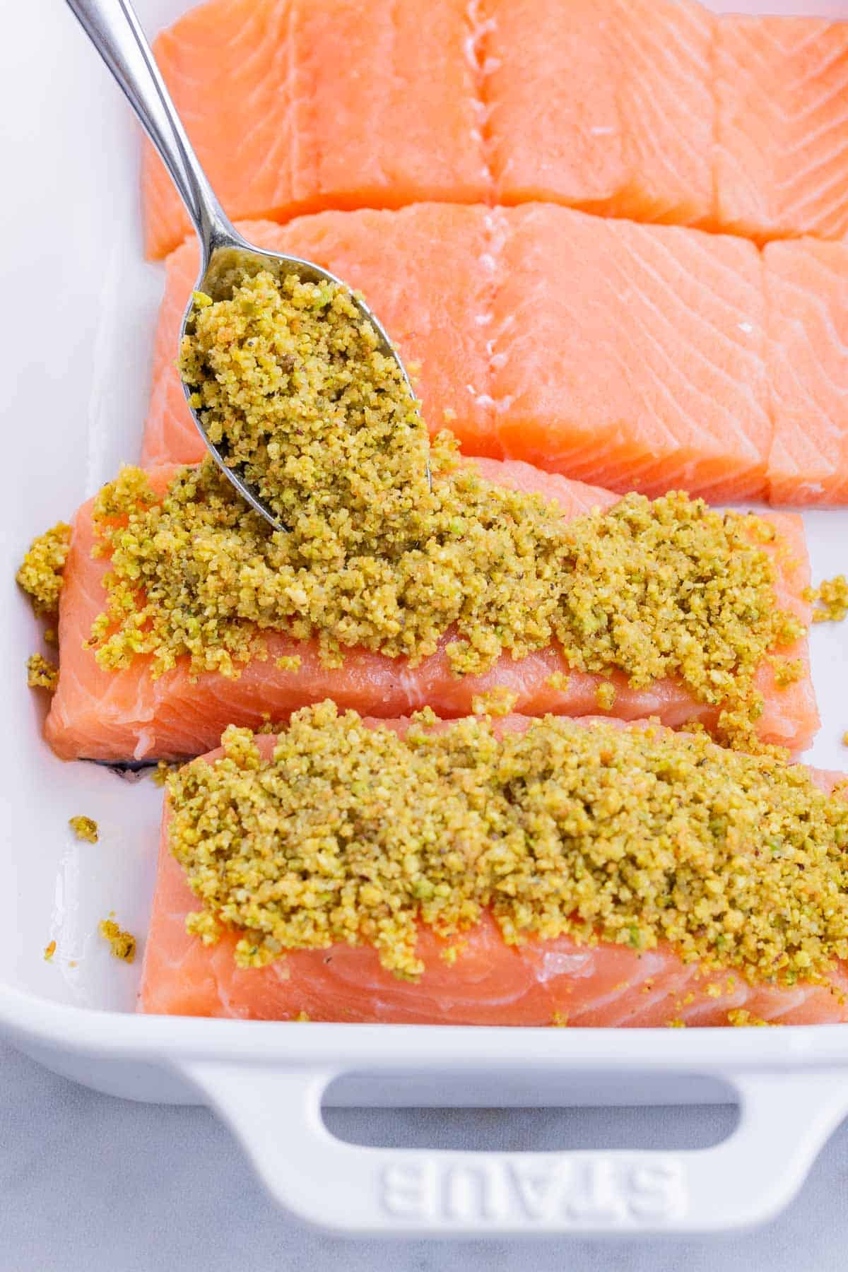 The pistachio is spooned on top of the salmon filets.