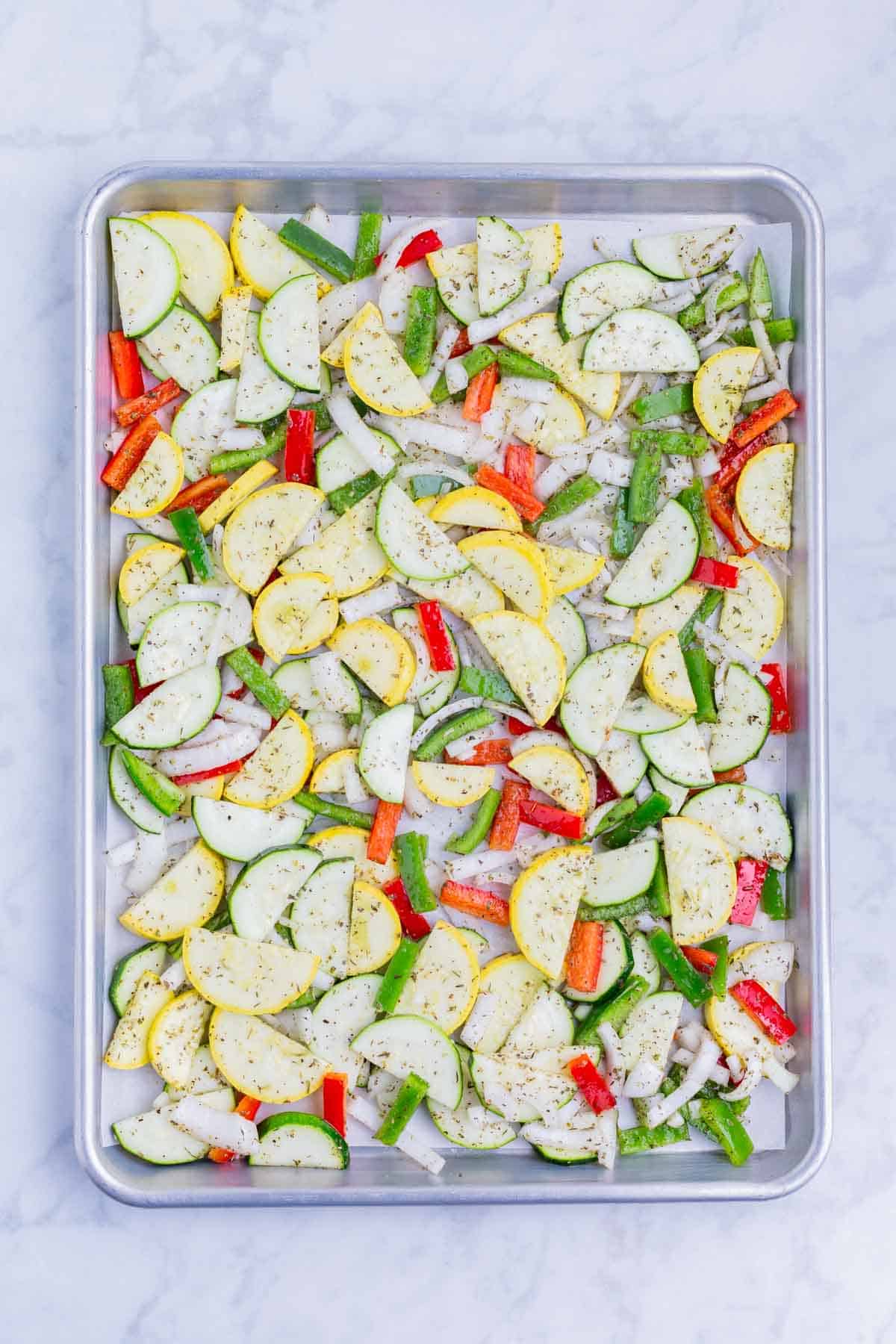 Sliced veggies are roasted on a baking tray in the oven.