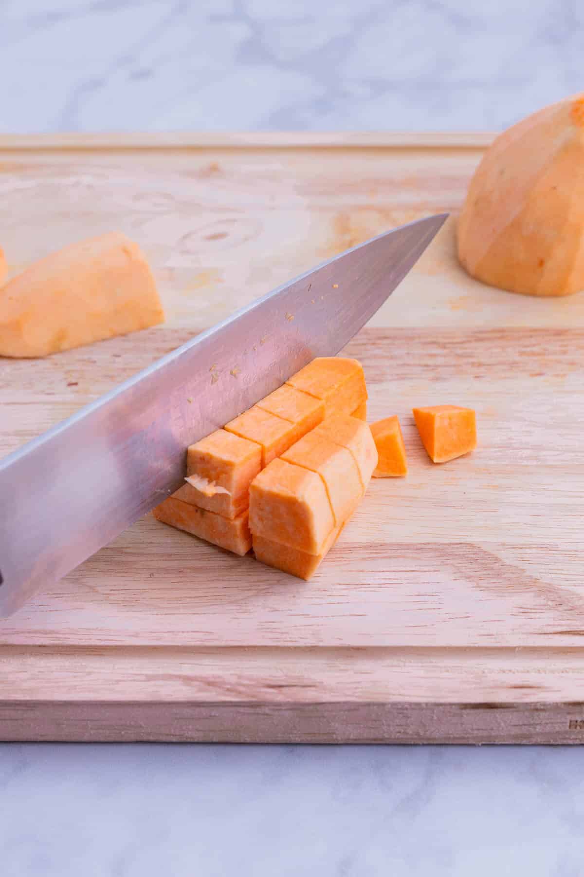 Sweet potatoes are diced on a cutting board.