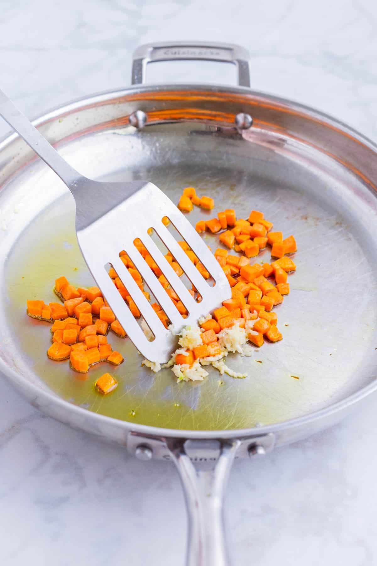 Carrots are sautéed in a skillet.