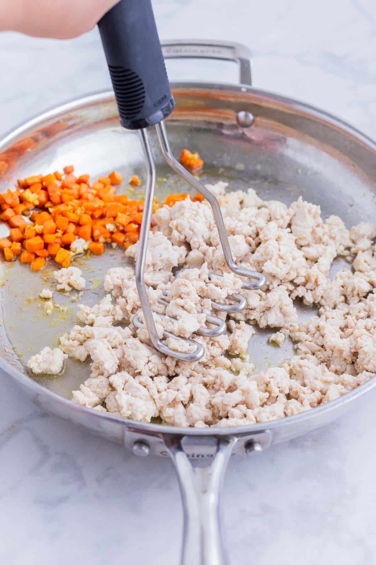 Chicken is browned and crumbled in a skillet.