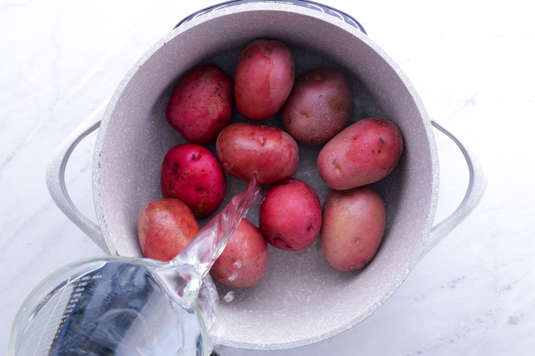 Red potatoes are added to a pot to boil.
