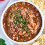A bowl of homemade roasted tomato salsa is served with tortilla chips.