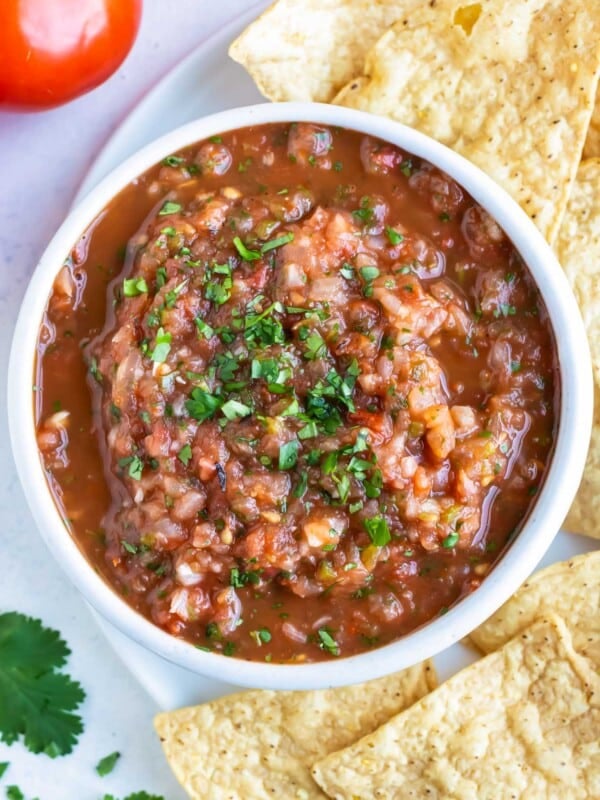 A bowl of homemade roasted tomato salsa is served with tortilla chips.