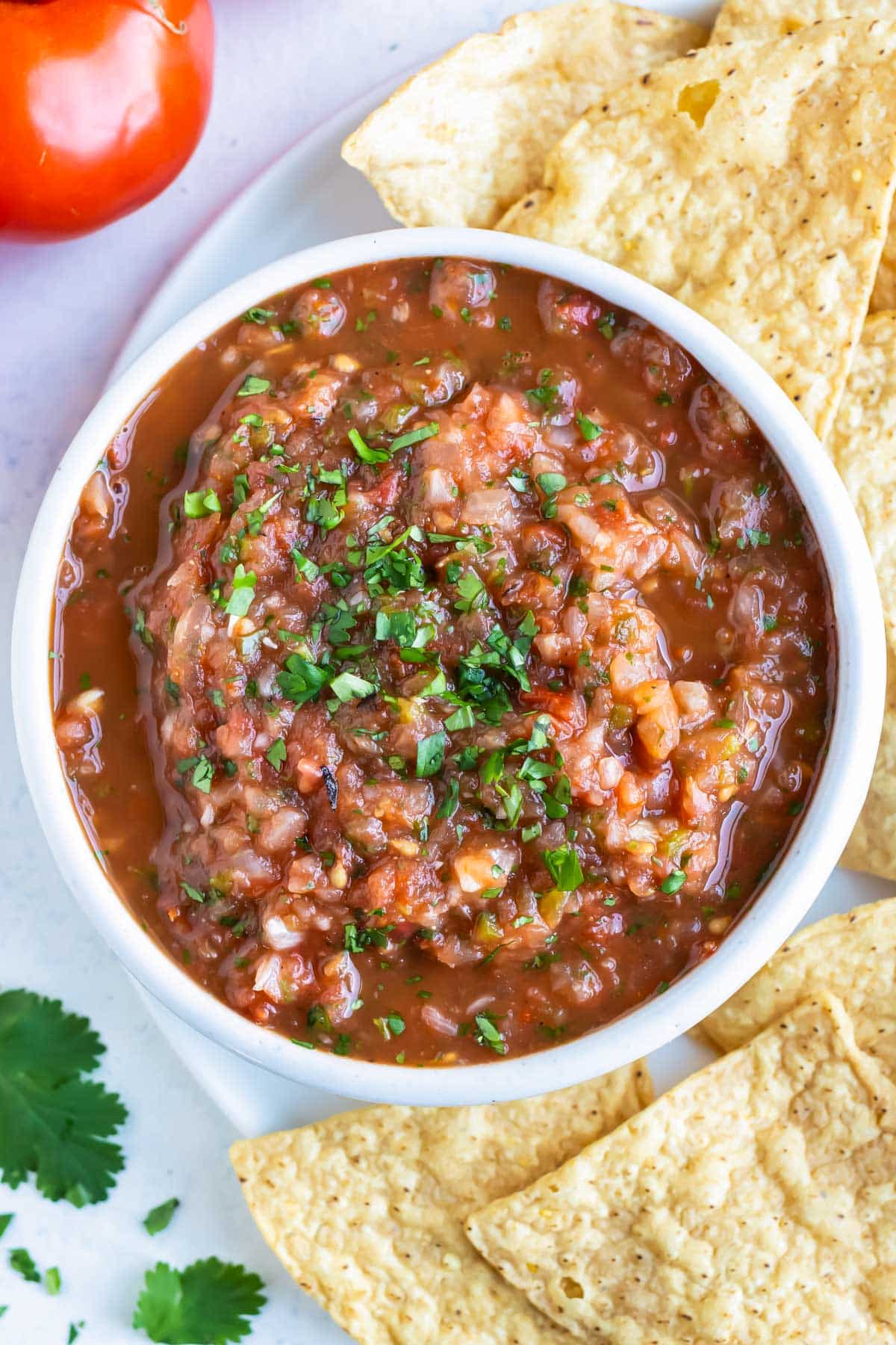 A bowl of homemade roasted tomato salsa is served with tortilla chips.