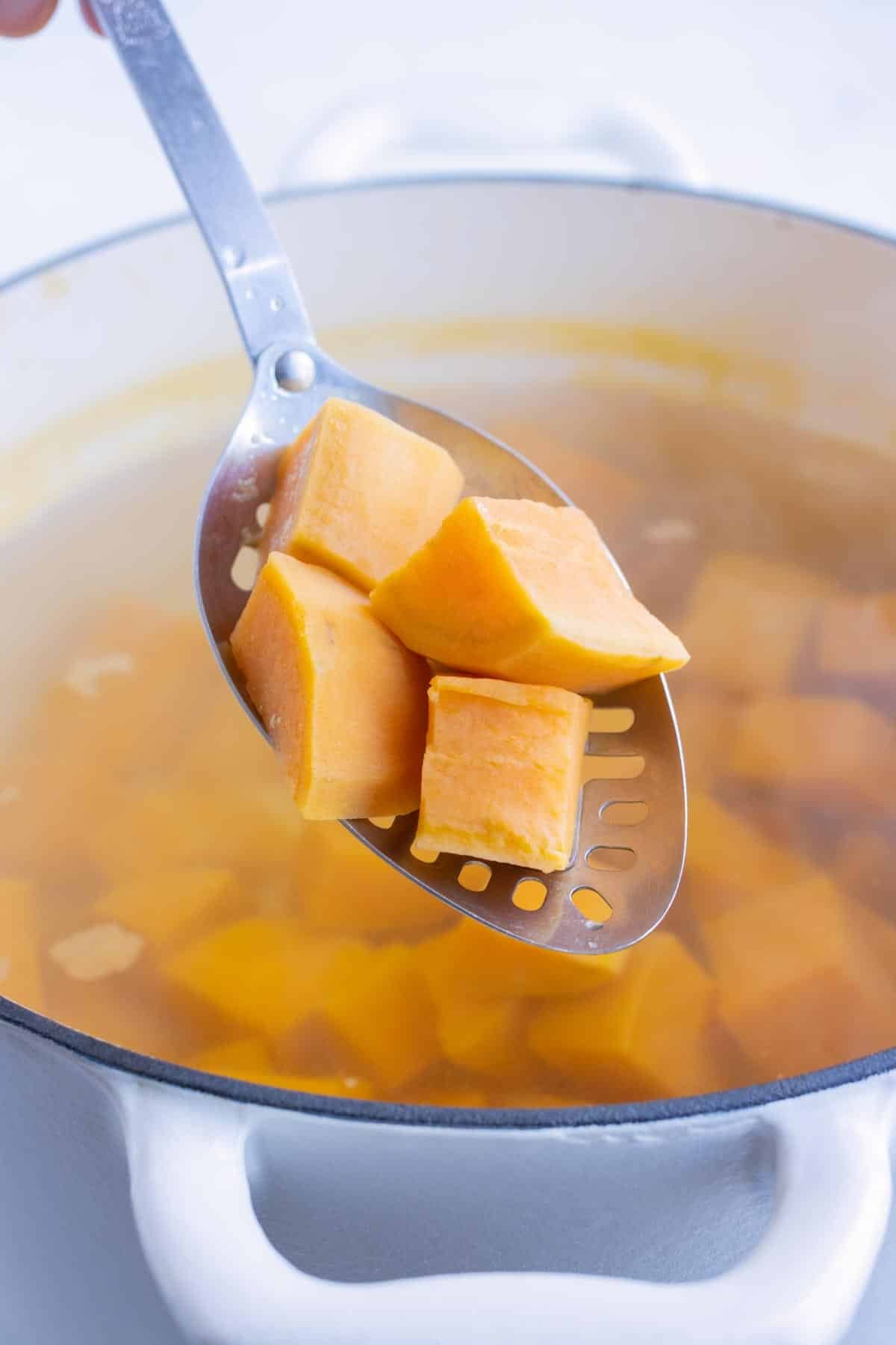 Tender sweet potatoes are removed from the water.