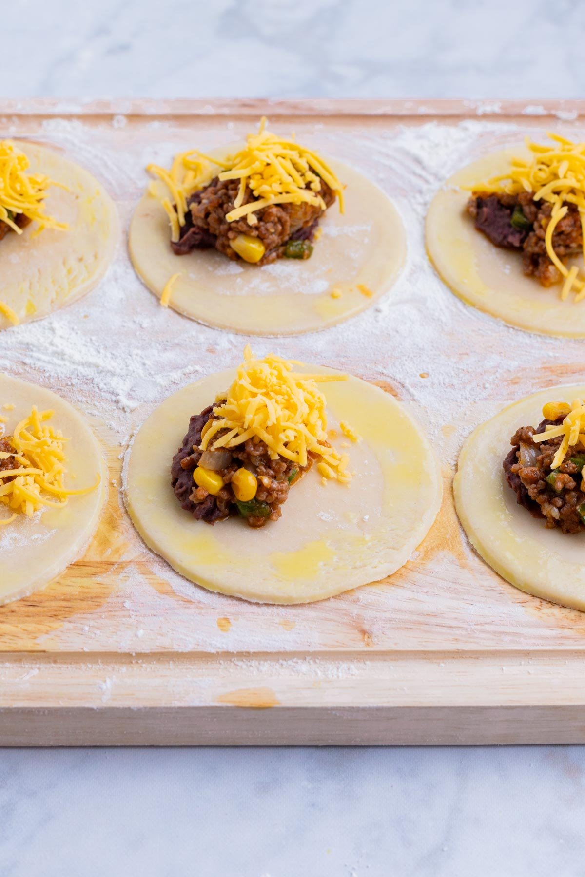 The beans, meat filling, and cheese are added to the middle of each pie crust circle.