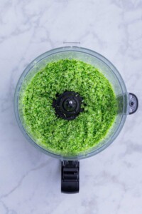Steamed broccoli is chopped in a food processor.