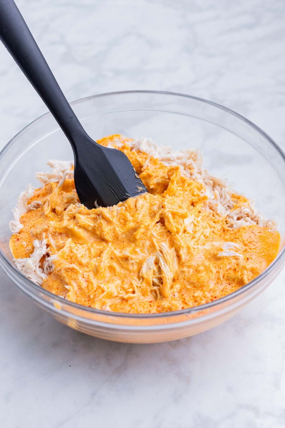 The buffalo sauce is poured over the shredded chicken.