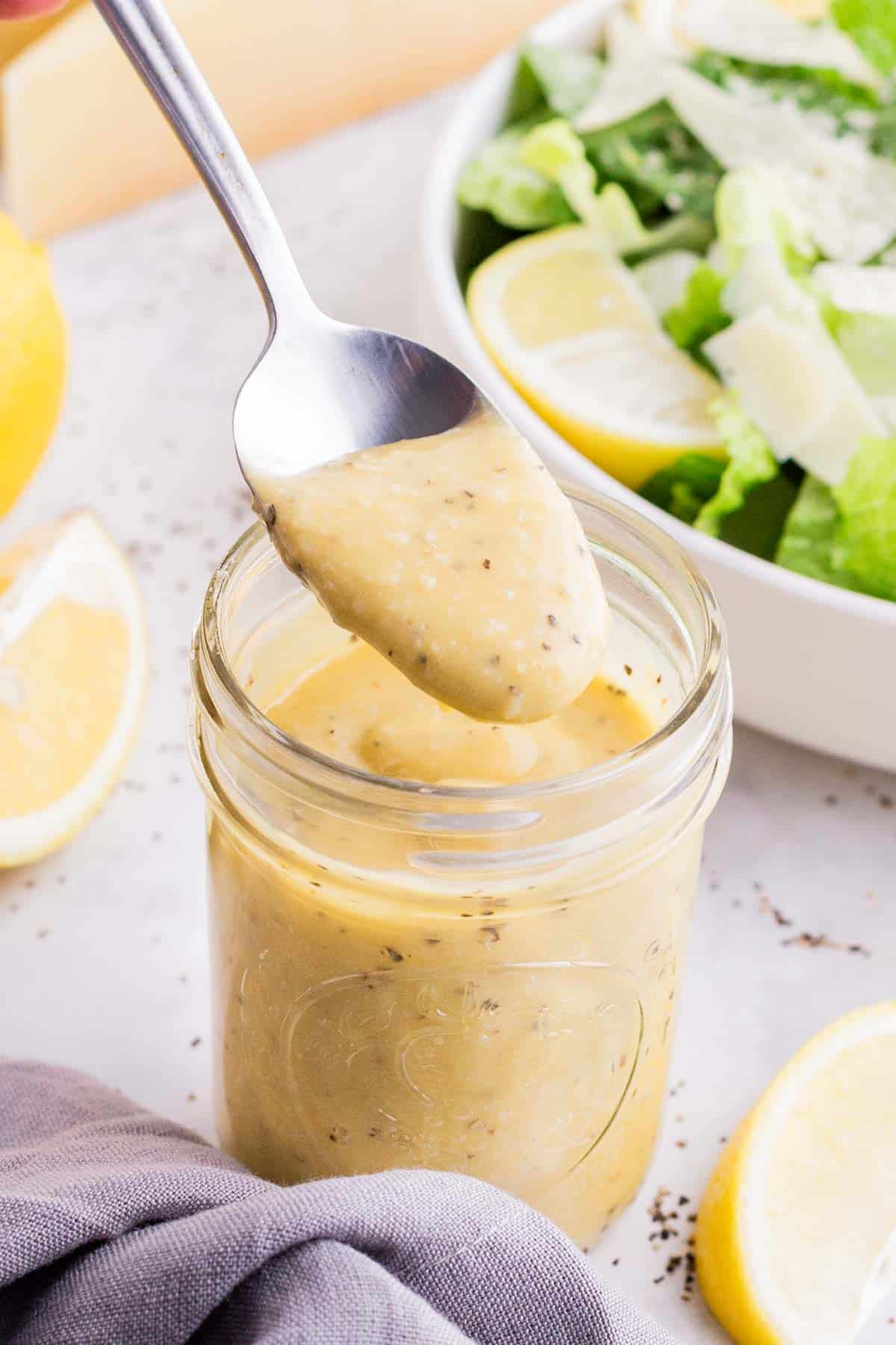 A spoon scoops out a serving of Caesar salad dressing.