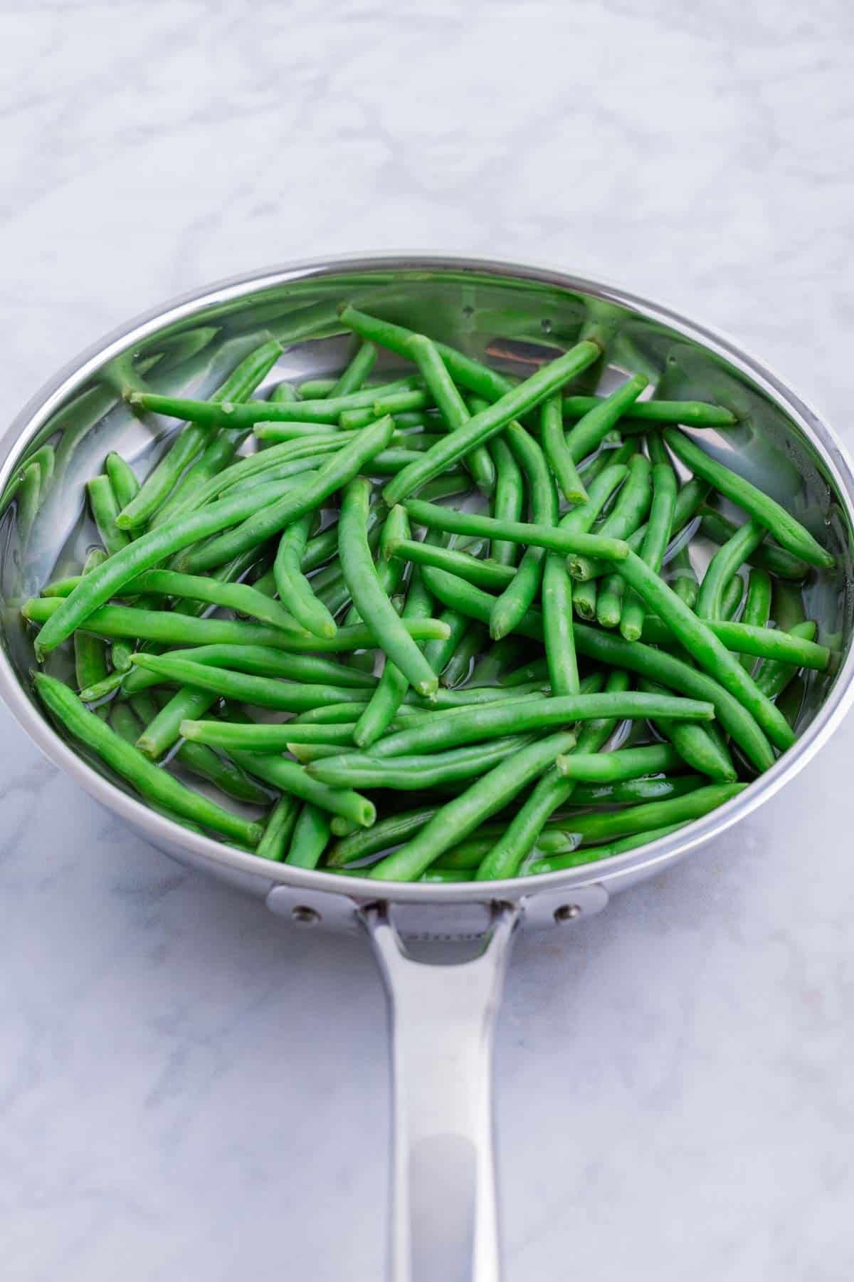 Green beans are quickly boiled in a skillet.