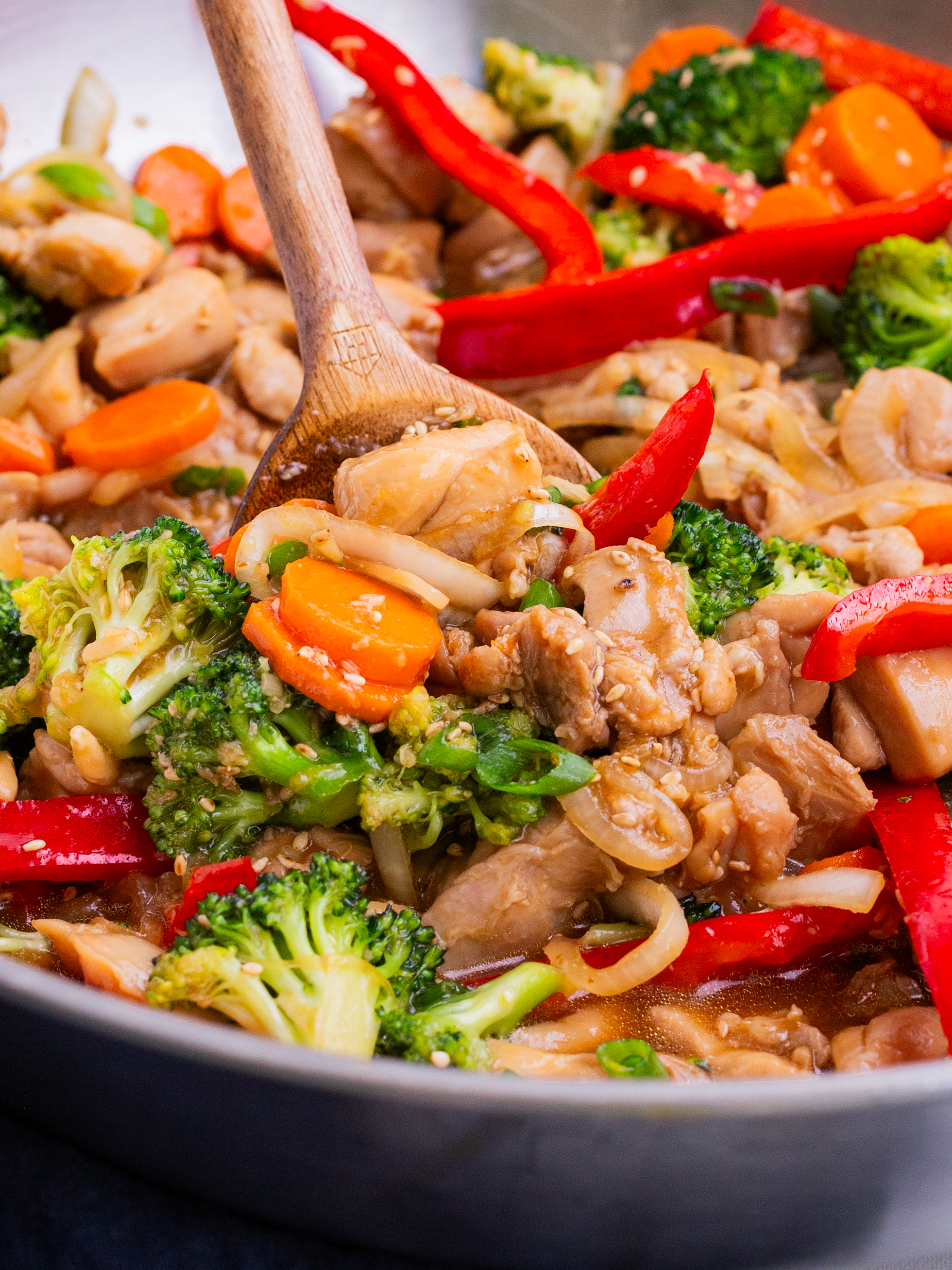 Chicken and veggies are simmered with a stir fry sauce in a skillet.