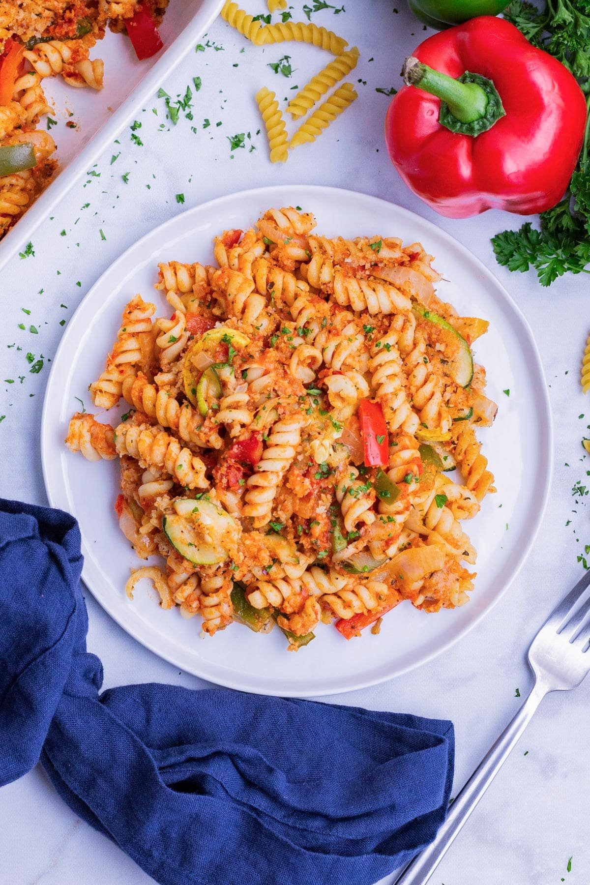 A roasted vegetable pasta bake is served in a white bowl.