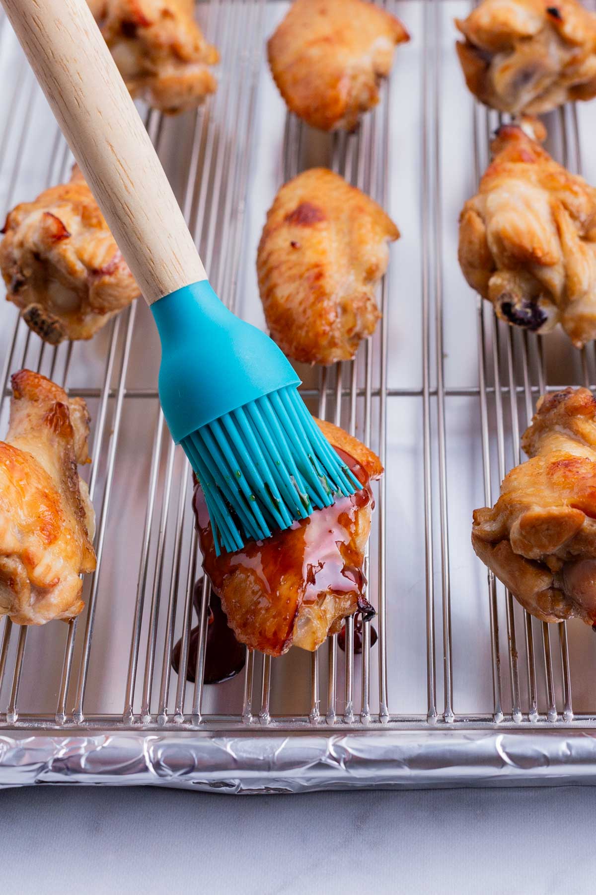 Chicken wings are basted with extra sauce before finishing.