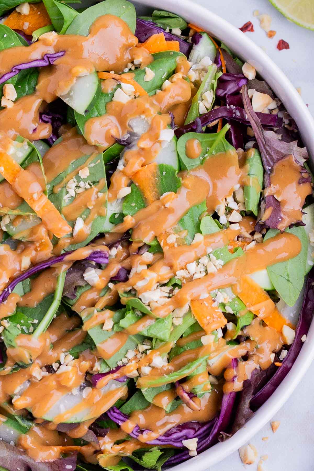 Red pepper flakes are dropped over the peanut dressing.