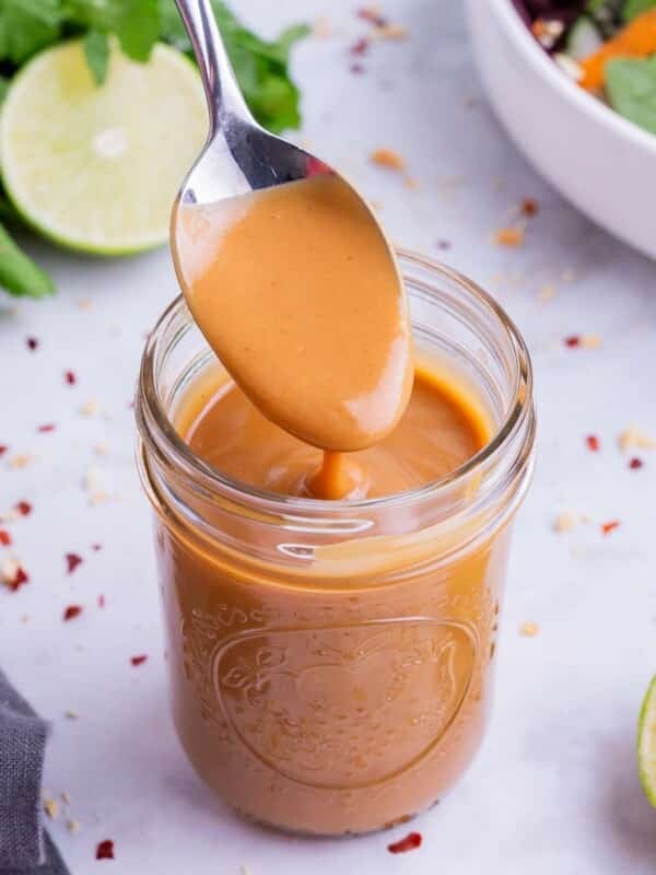 Thai peanut dressing being lifted up out of a mason jar.