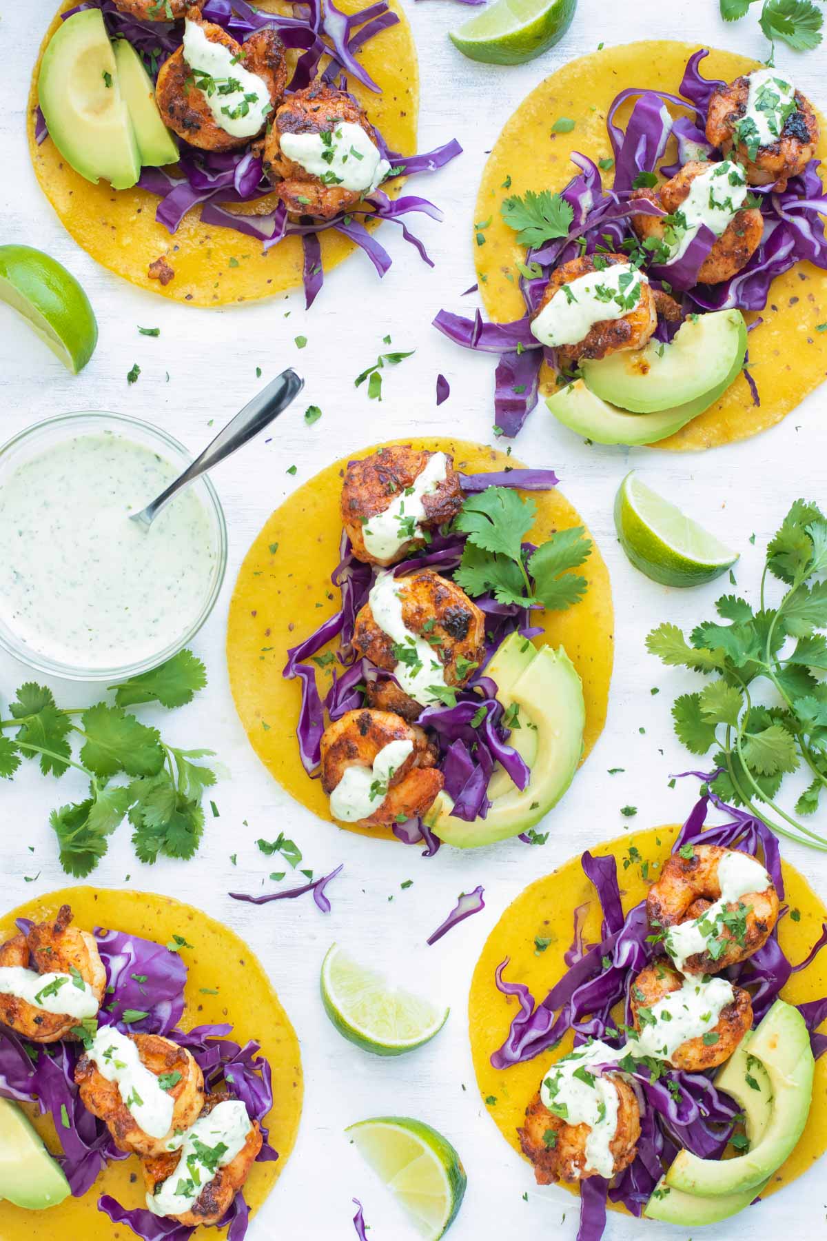 Easy Blackened Shrimp Tacos for dinner on a white table with sauce.