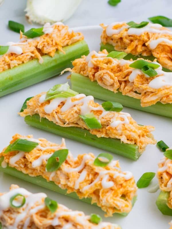 Celery sticks are loaded up with buffalo chicken dip and drizzled with ranch dressing and green onions.