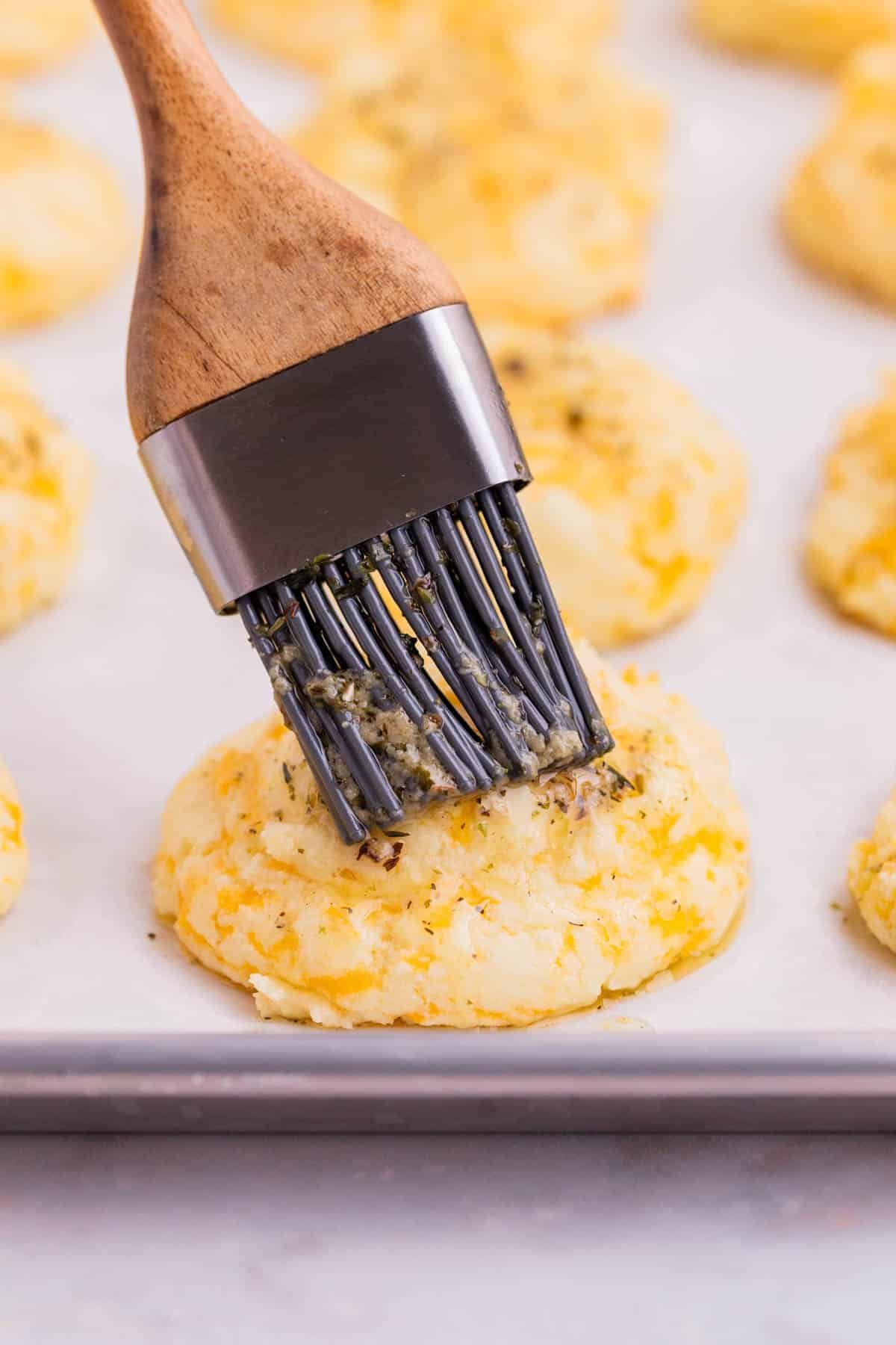 Butter is brushed on the freshly baked biscuits.