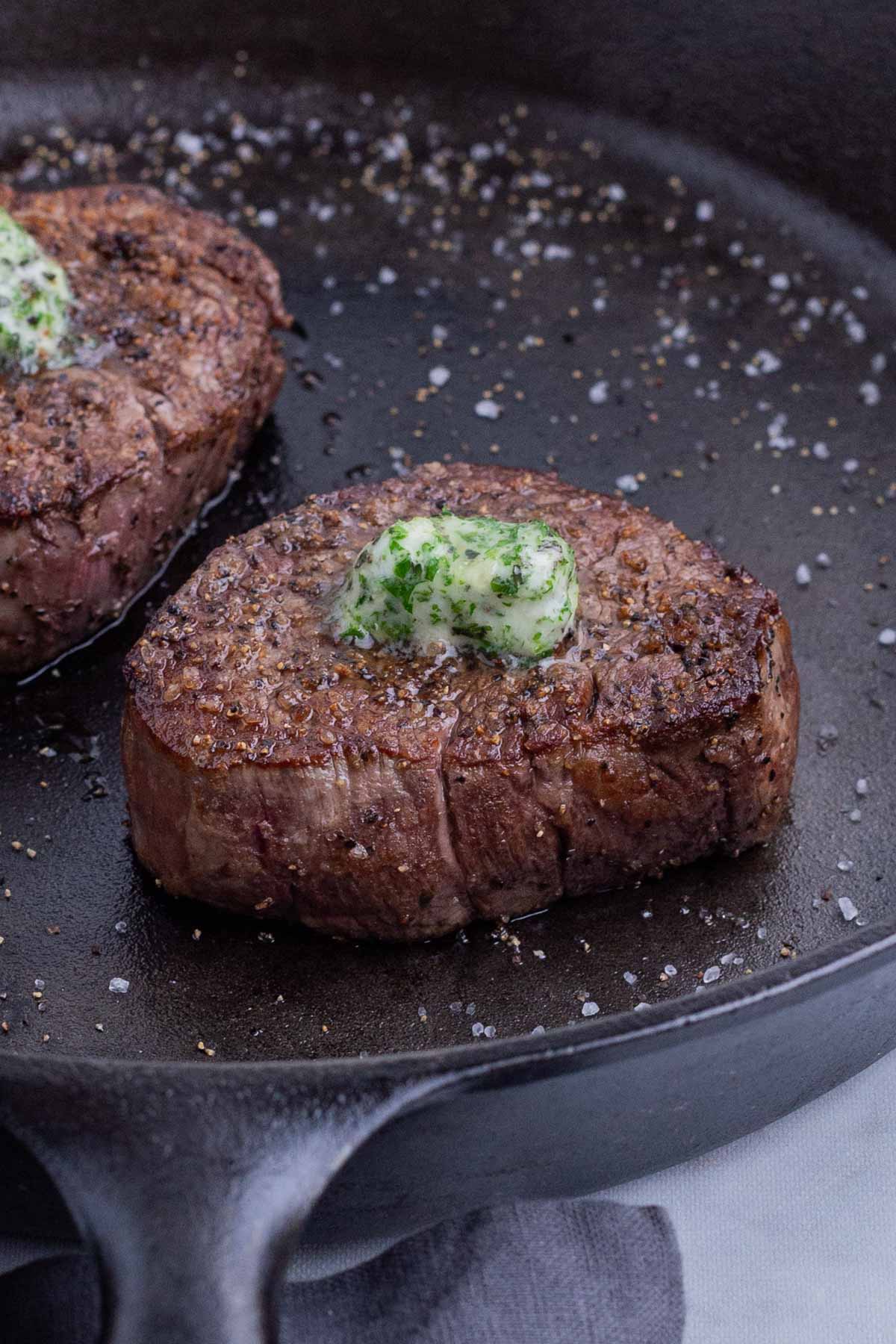 Garlic herb butter on a filet mignon recipe in a cast iron skillet.