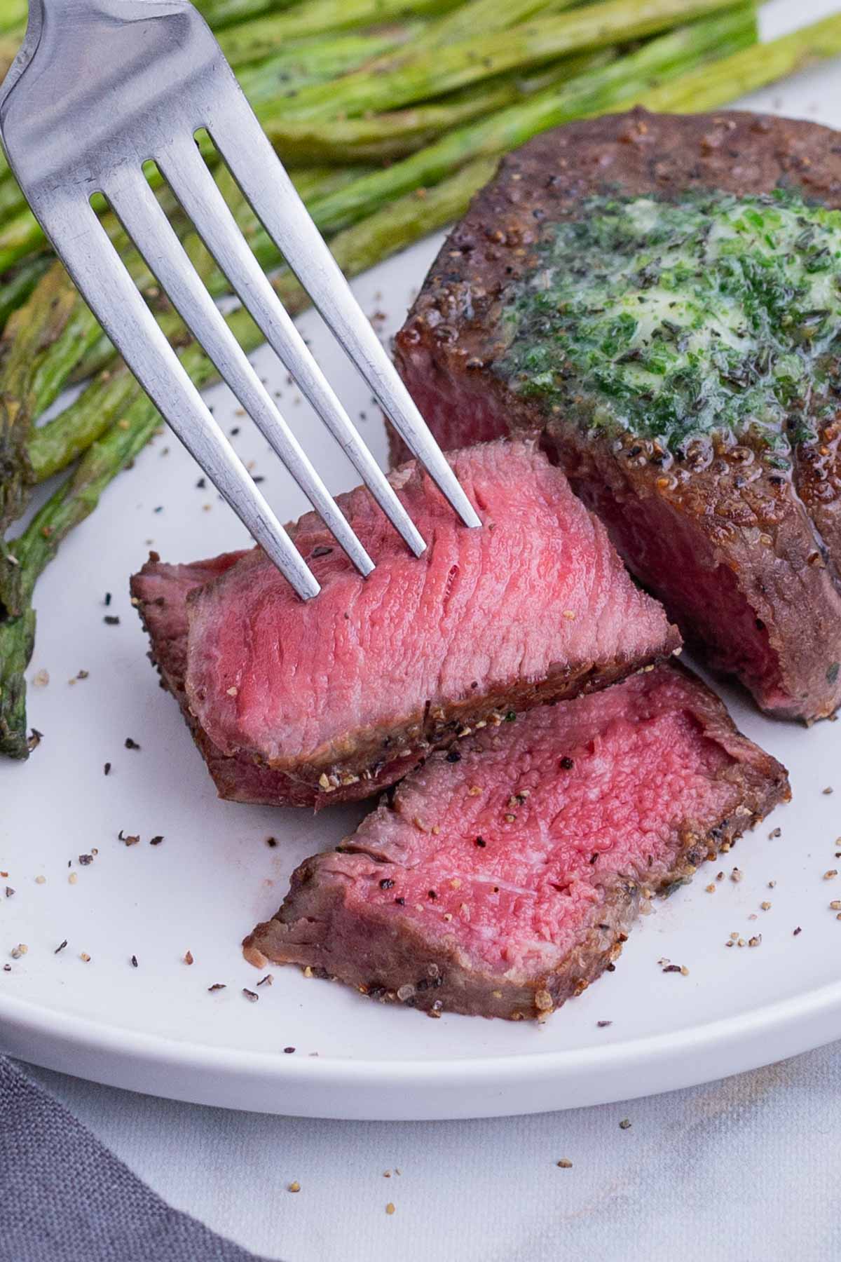 A medium rare steak is cut on a plate.