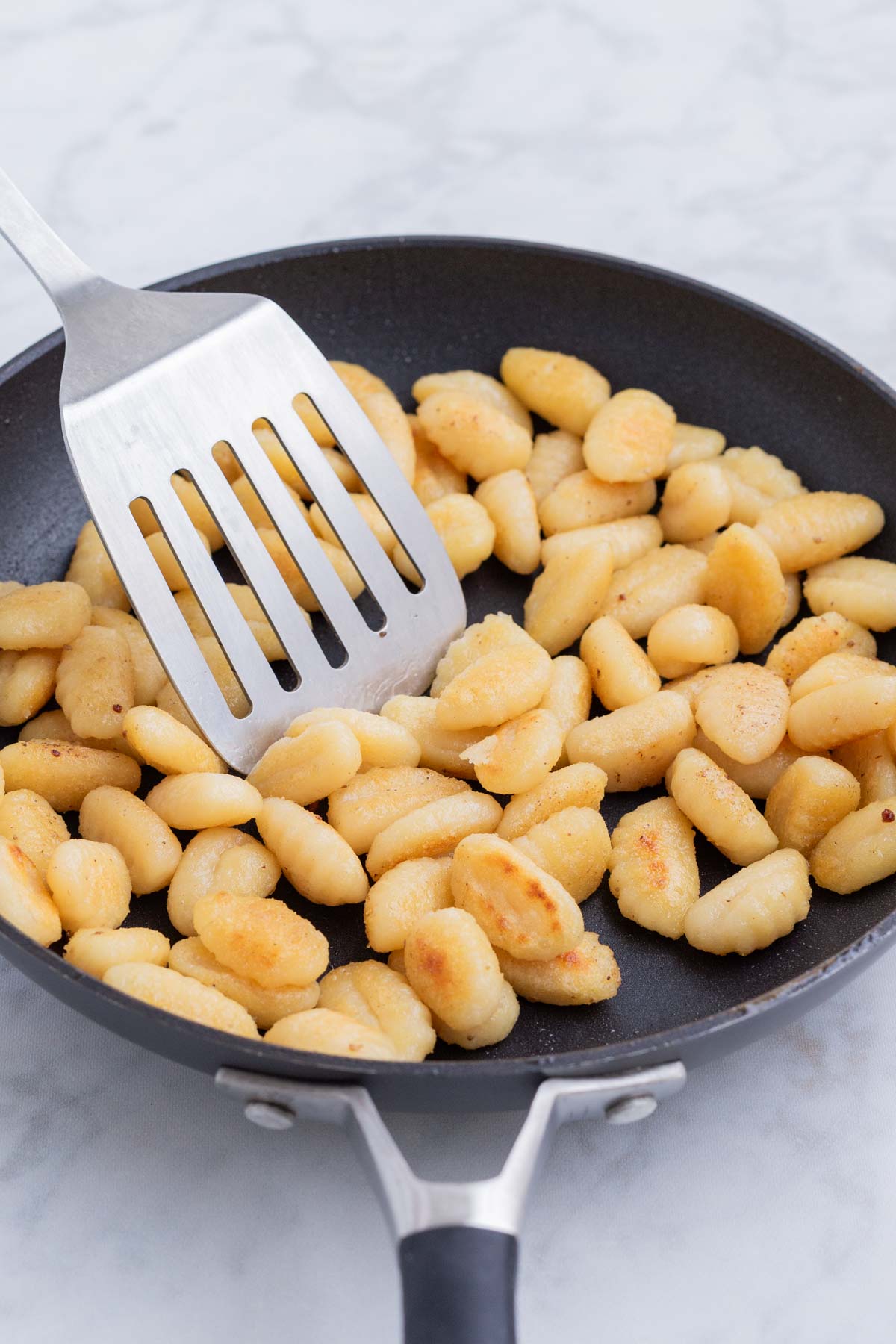 Gnocchi is seared in a skillet.