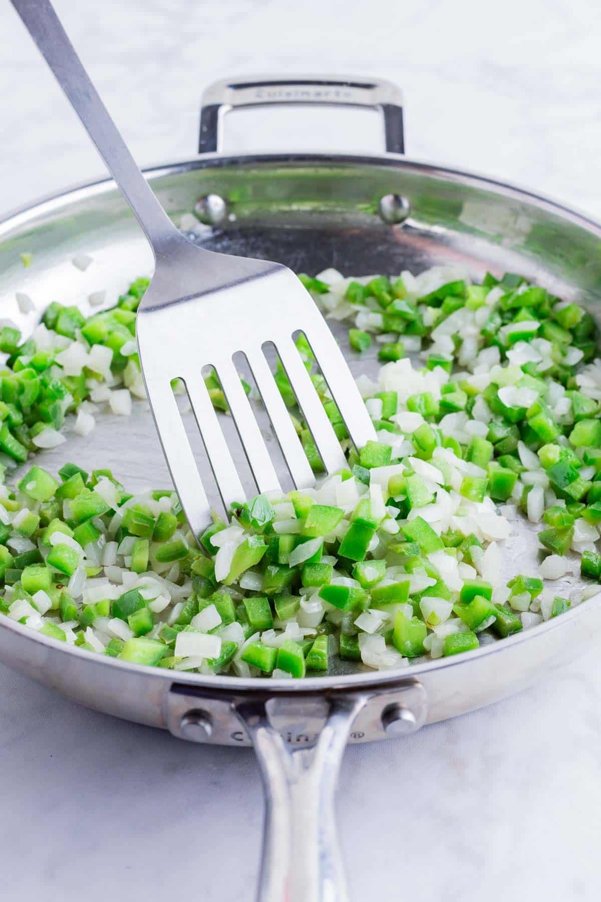 Peppers and onion are sautéed in a skillet.