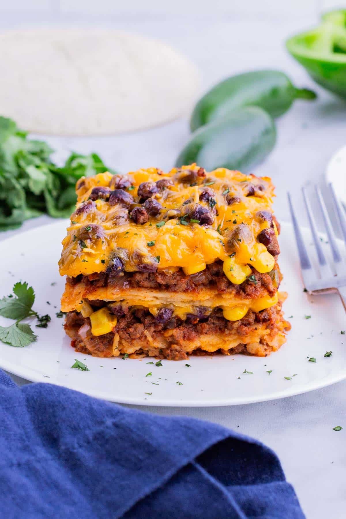 A single serving of Mexican lasagna is served on a white plate.