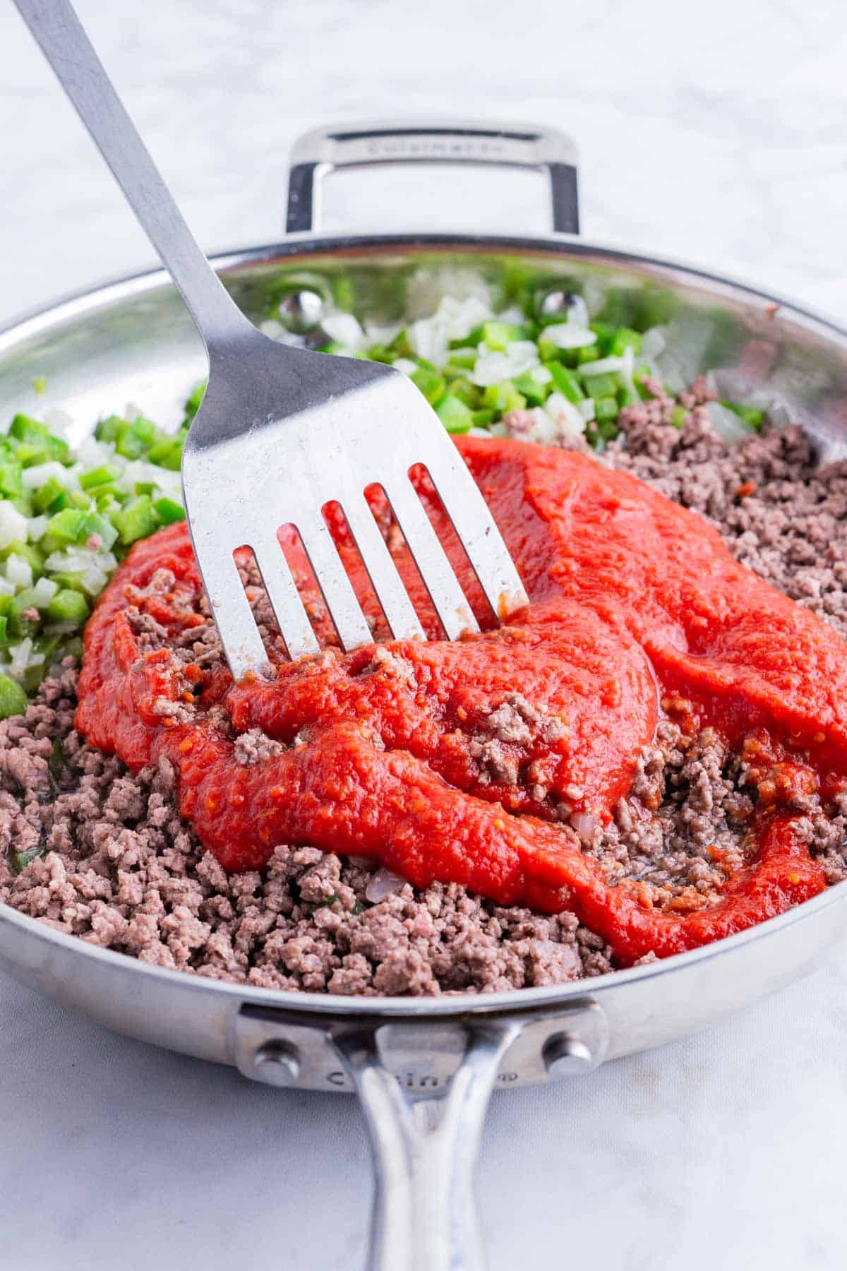 Tomato sauce is stirred into the meat mixture.