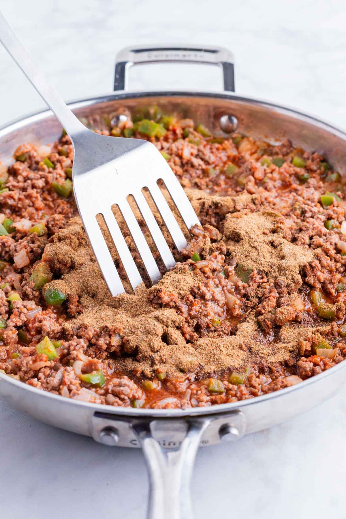 A spatula stirs spices into the meat for Mexican Lasagna.