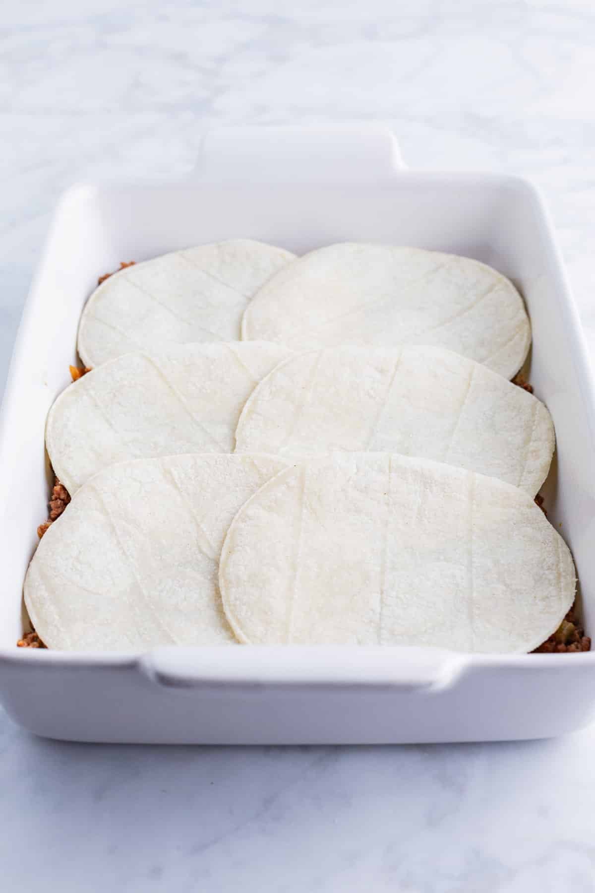 Corn tortillas are spread in a dish.