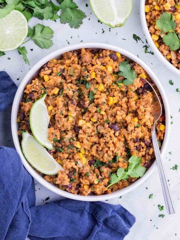 Mexican beef and rice is served with fresh lime wedges.