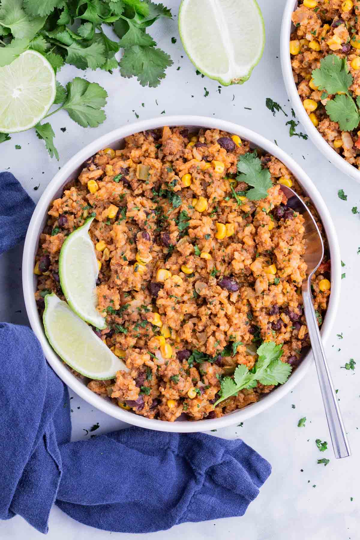 Easy Mexican Beef and Rice Skillet RECIPE served in a white bowl with a spoon topped with lime.