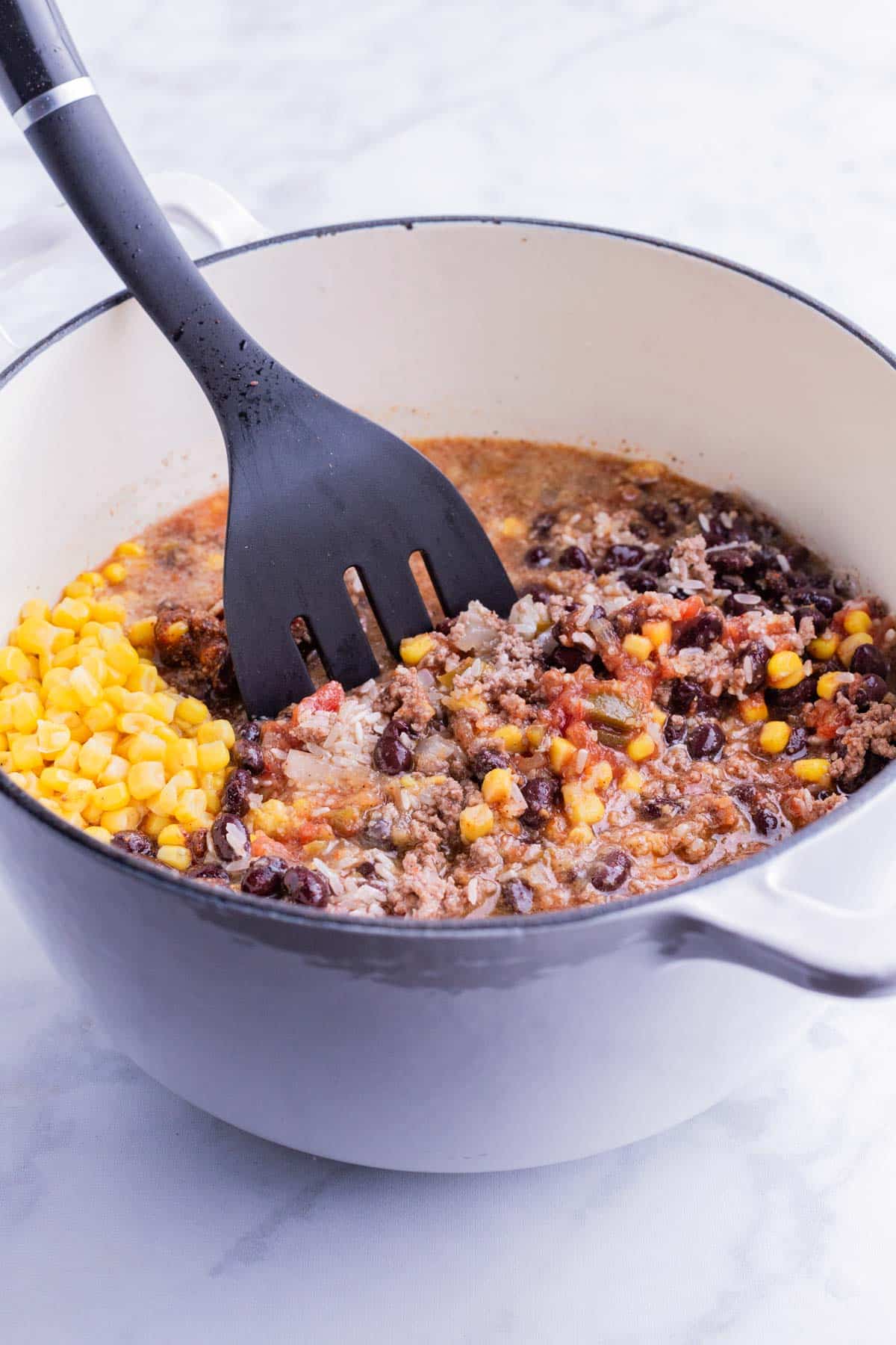 Rice, corn, black beans, seasonings, and the beef are added back into the pot.