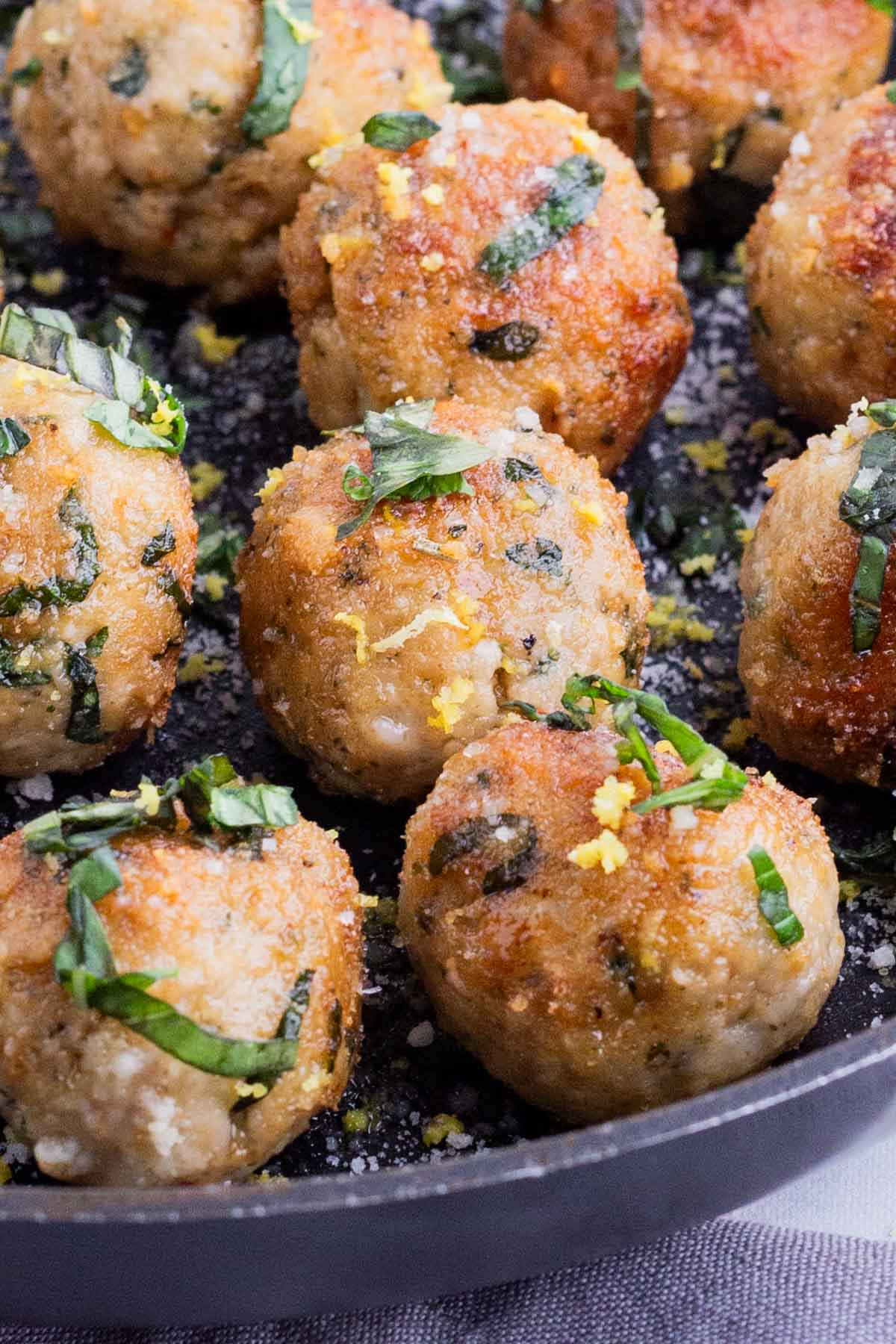 Chicken meatballs are cooked in a skillet.