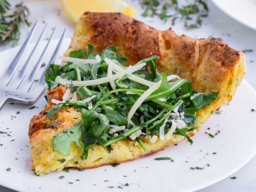 A slice of savory Dutch baby is served on a white plate.