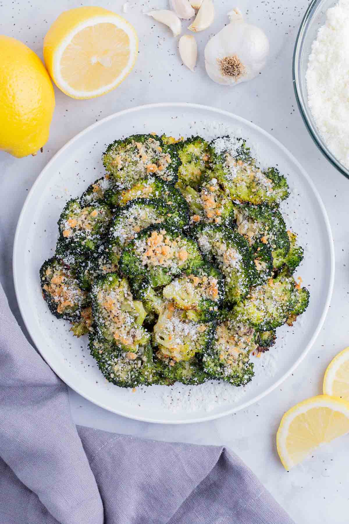 Smashed broccoli with Parmesan is served on a white plate.