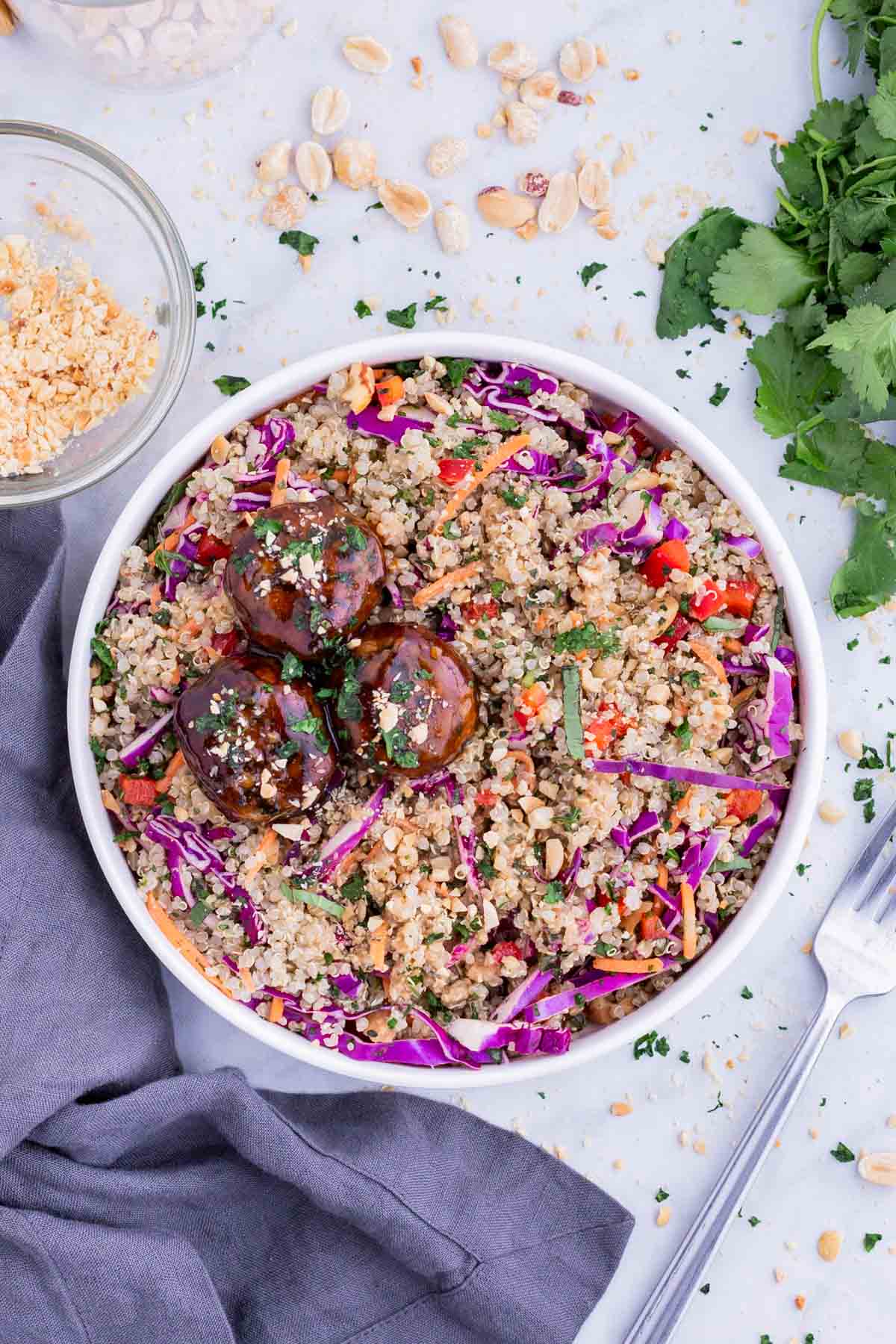 Thai meatballs are served in a white plate with quinoa salad.