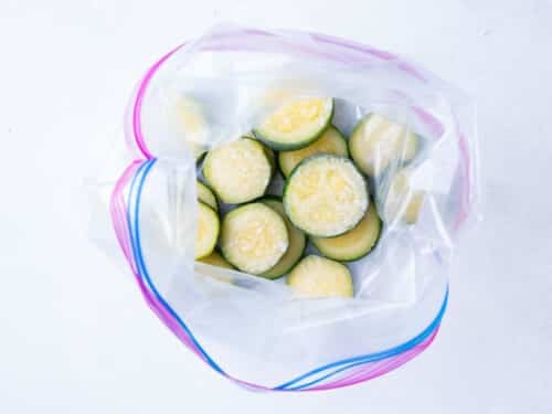 Sliced zucchini is placed into a freezer ziplock bag for keeping in the freezer for future recipes.