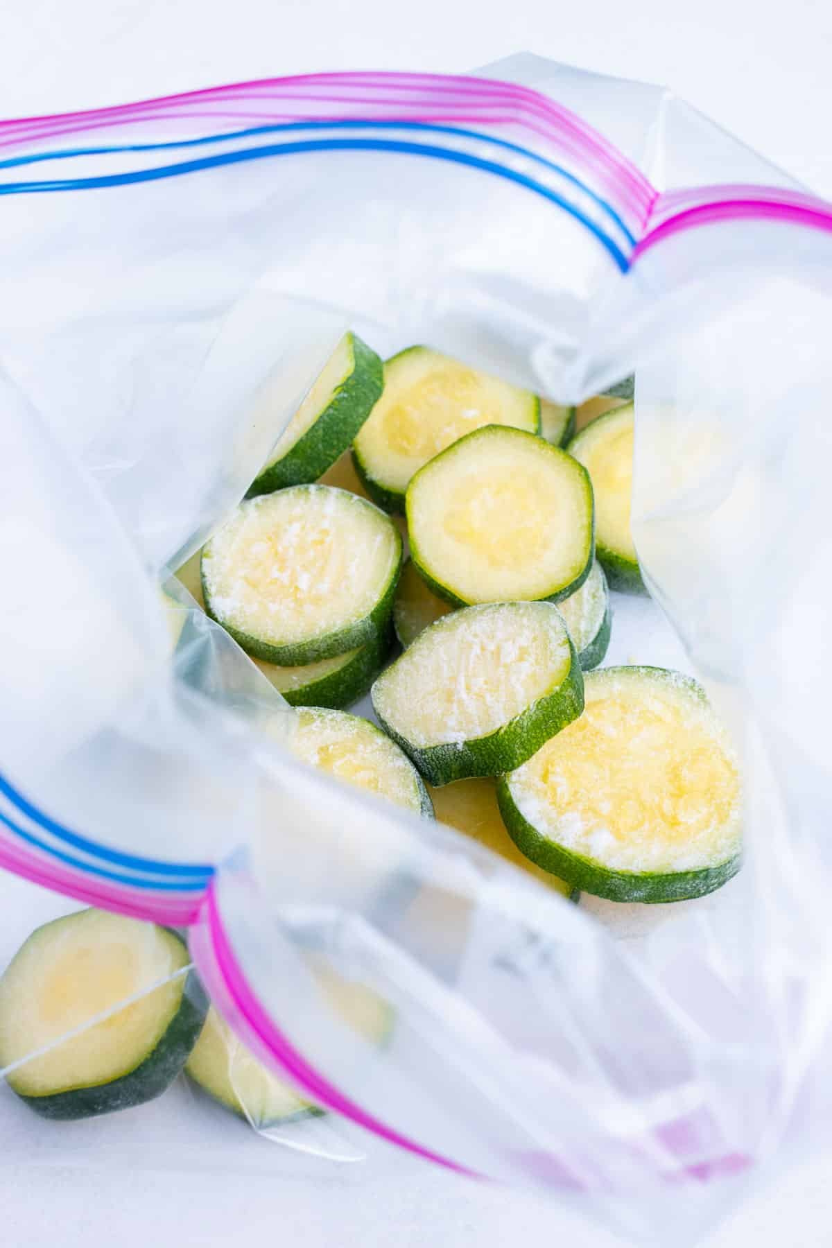 Frozen zucchini slices are stored in a ziplock freezer bag.