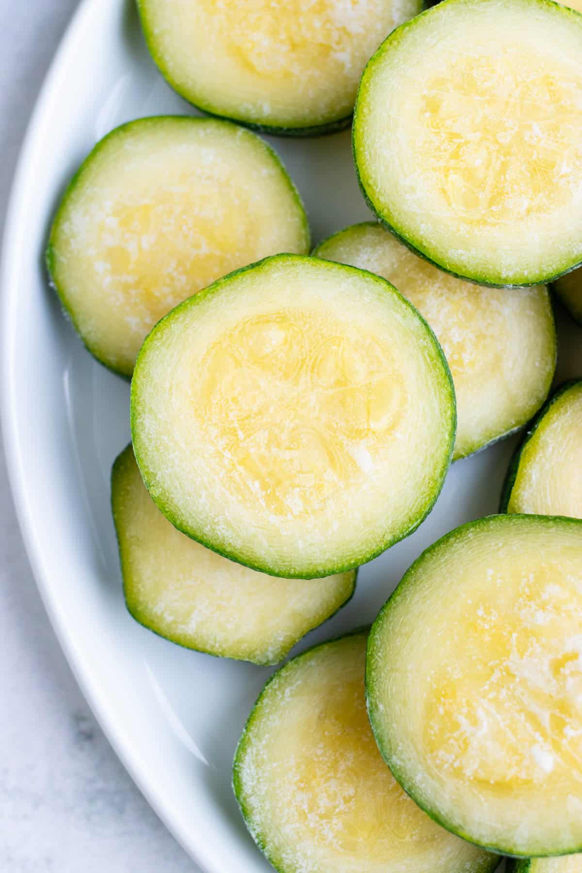 Fresh zucchini was frozen and the slices are now stacked on top of each other on a plate.