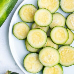 Frozen zucchini is stacked on a white plate on the counter.